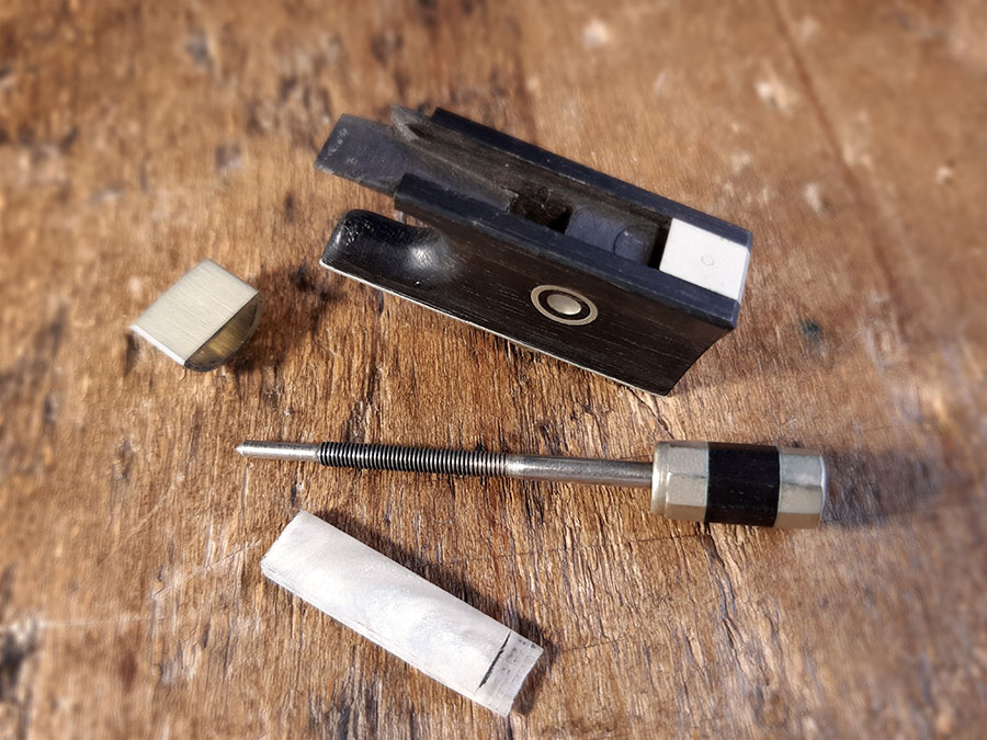 Une hausse d'archer démontée : hausse, bouton, plaque de recouvrement et passant.