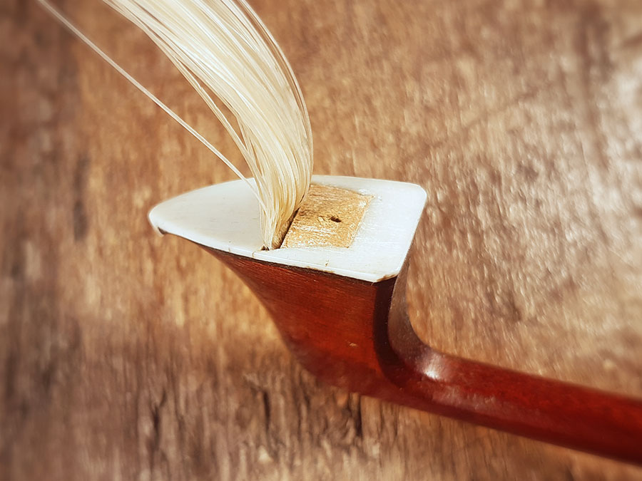 La tête d'un archet : on voit la petite cale taillée sur mesure pour bloquer la mèche dans la mortaise.